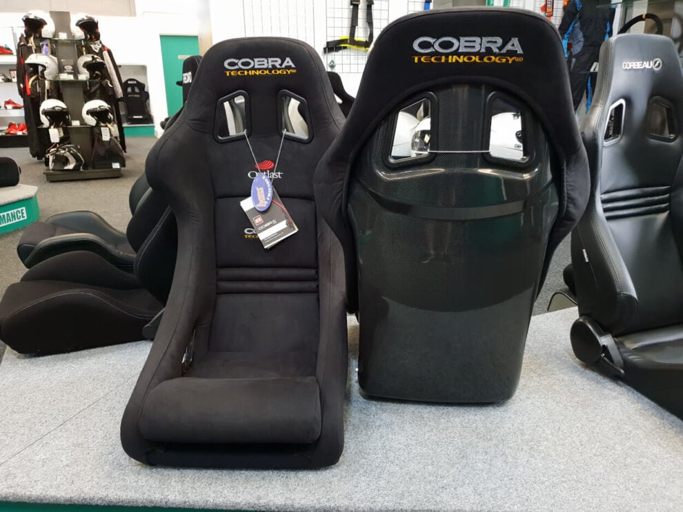 Two black Cobra Imola Technology bucket seats on the showroom display, one facing forward and one showing its carbon finish back