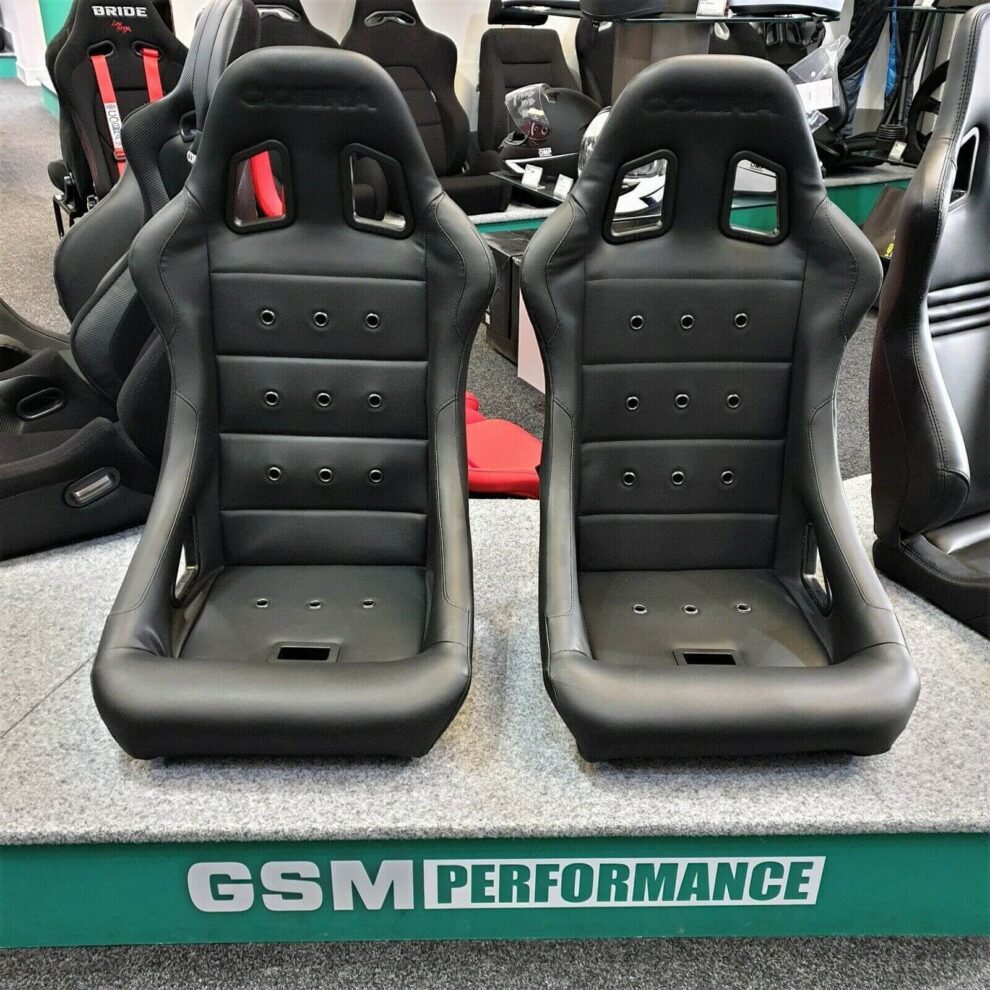 Front view of the two black Cobra Monaco Pro 40th Edition seats showing the ribbed backrest with eyelets and the embossed Cobra logo