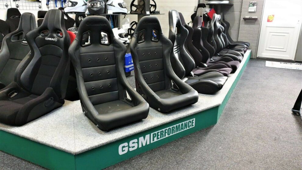 Two black vinyl Cobra Monaco Pro 40th Edition bucket seats on the GSM Performance showroom display plinth among other seats