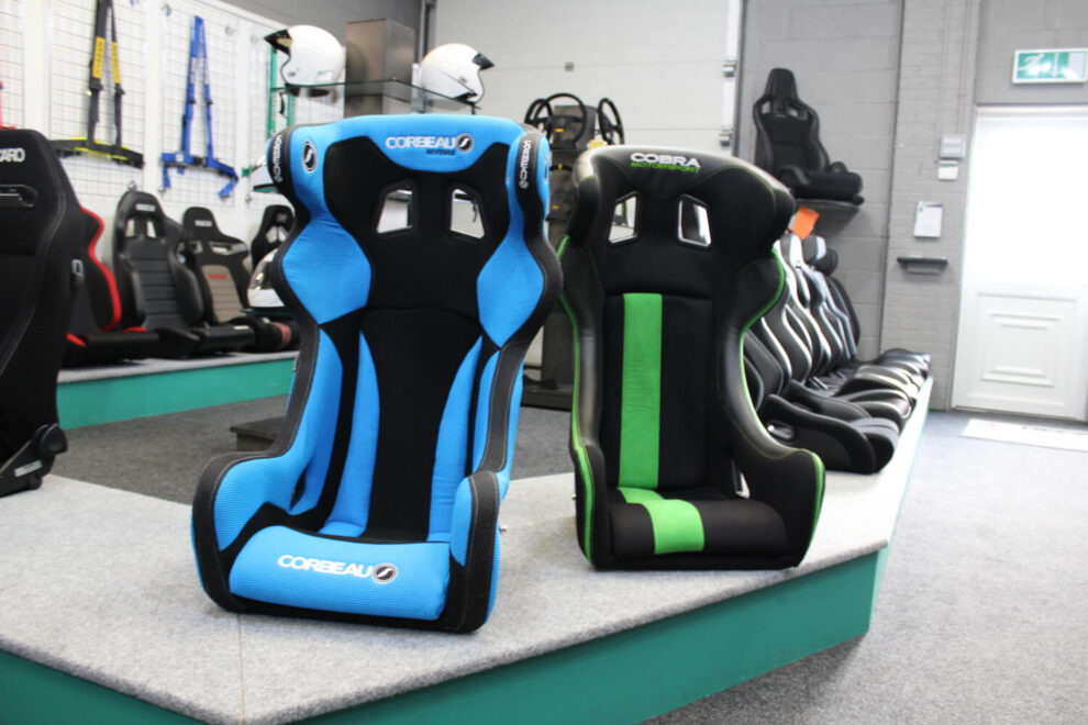 A blue and black Corbeau Revenge and a black and green Cobra Sebring bucket seat side by side on the showroom display