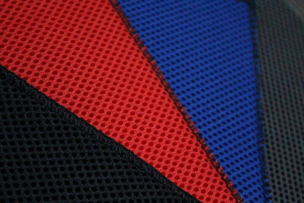 Close-up of black, red and blue spacer fabric panels stitched together on a seat