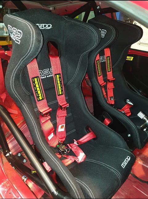 Two black Mirco RS2 Limited Edition bucket seats with red Schroth harnesses fitted inside a caged red Honda Civic