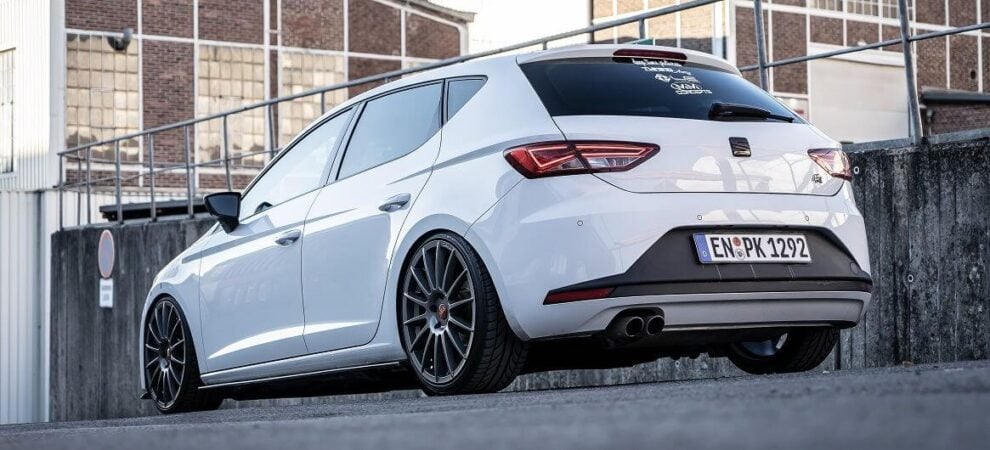 The rear three quarter view of a white Seat Leon 5F with dark grey wheels