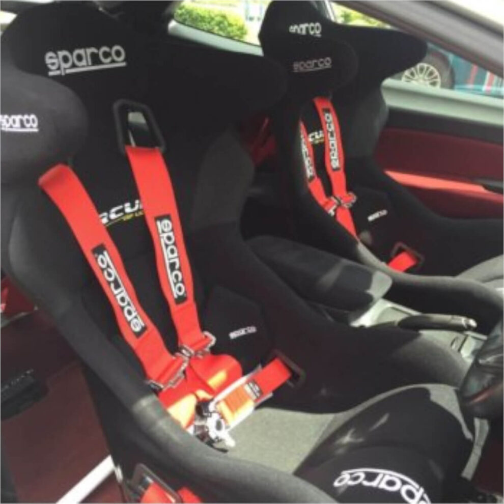 Black Sparco bucket seats with red Sparco harnesses fitted in a car with a red interior