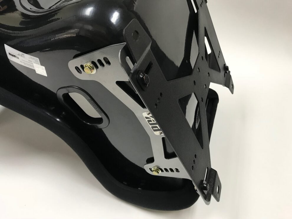 Underside view of a black Momo bucket seat showing the PCI side mounts bolted to the shell and the black base plate across the bottom