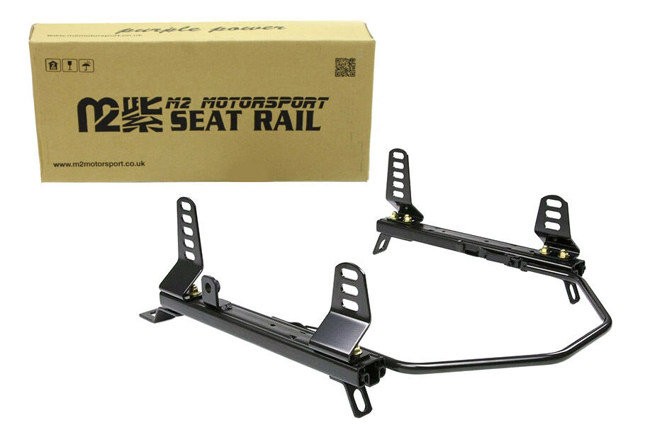 A black M2 Motorsport seat rail with side mount brackets and sliding runner in front of its cardboard box, on a white background