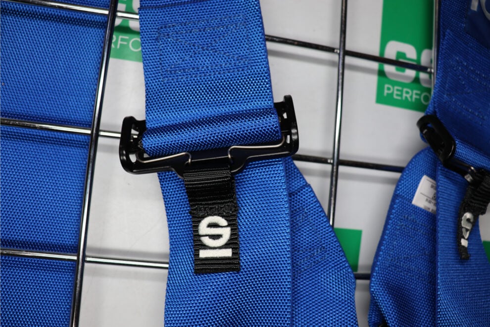Close up of a blue Sparco harness strap running through a black webbing adjuster with a Sparco pull tab