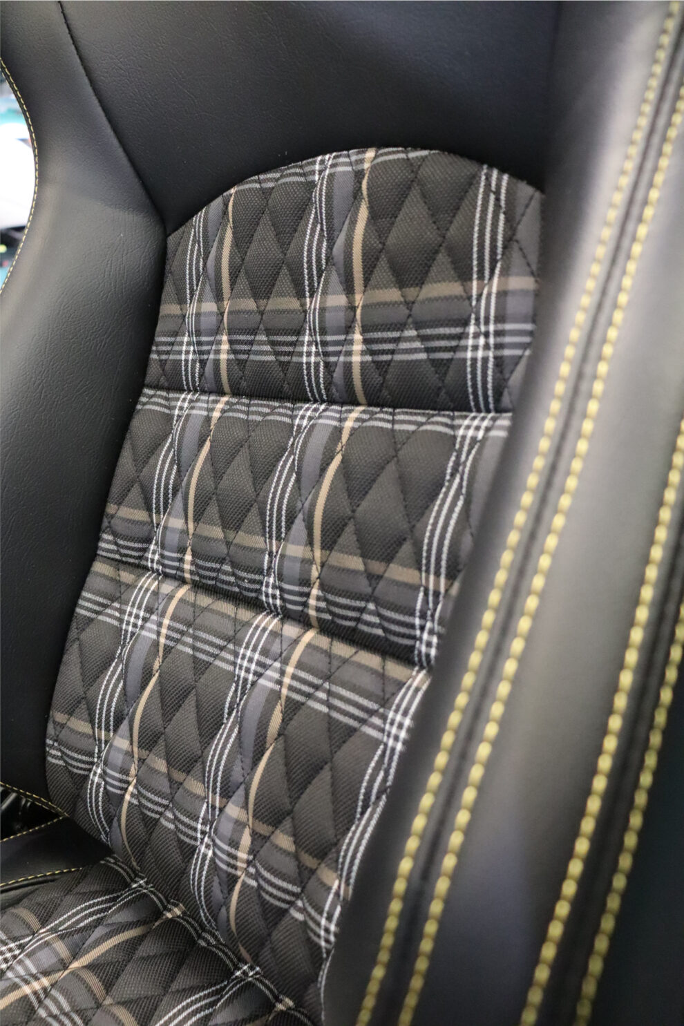 Close up of the diamond quilted yellow and grey tartan backrest of an Auto Style GT seat, with yellow stitching along the black vinyl bolster