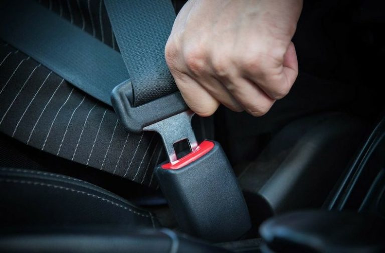 Driver plugging a seat belt buckle home in a car