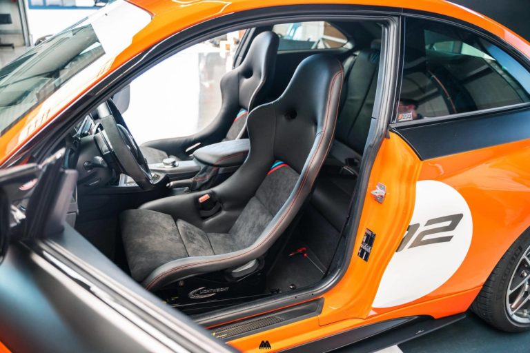 Fixed back bucket seats fitted in an orange BMW road build, seen through the open door
