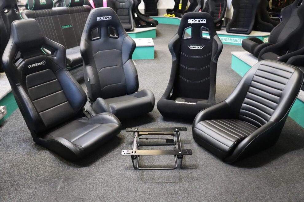 A Corbeau reclining seat, a Sparco reclining seat, a Sparco Sprint bucket and an OMP low back seat arranged around a Cobra Classic Mini subframe on the GSM Performance showroom floor