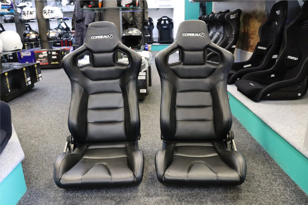 A pair of black Corbeau RRS reclining seats with blue stitching on the floor of the GSM Performance showroom