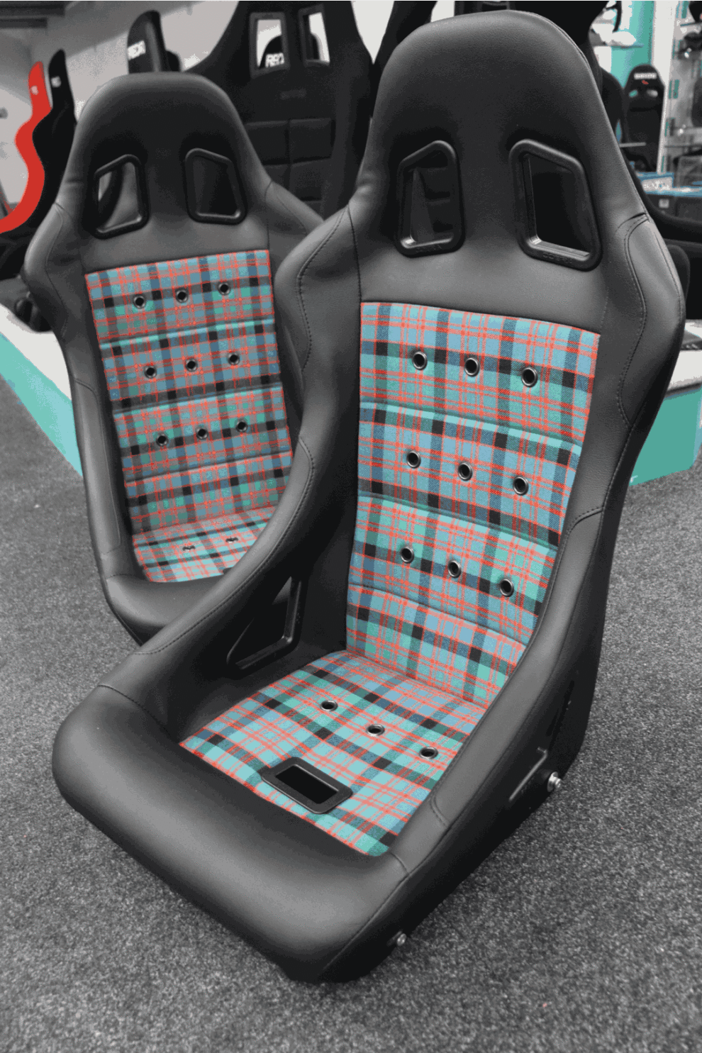 Two Cobra Monaco 40th Edition bucket seats in customer supplied tartan on the showroom floor, seen from an angle
