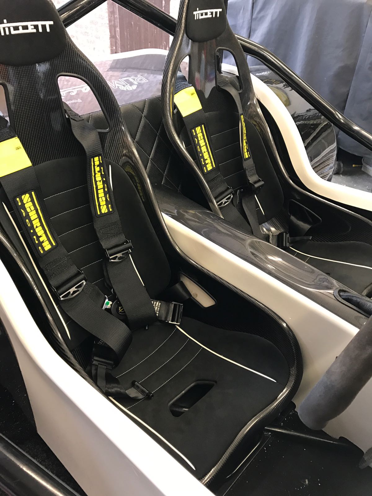 Two Tillett B6 Carbon bucket seats fitted in a customer MNR Vortx Seven style kit car, with Schroth four point harnesses bolted in and the roll bar behind
