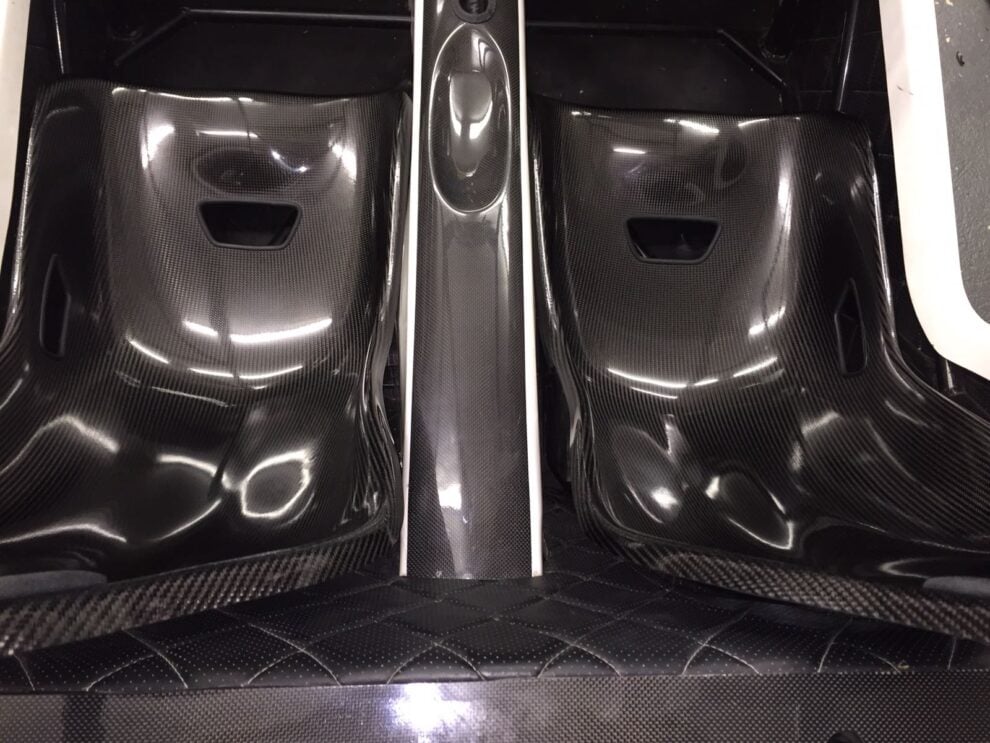 Looking down on two carbon Tillett B6 bucket seats fitted either side of the transmission tunnel in a Seven style kit car, with very little room between them