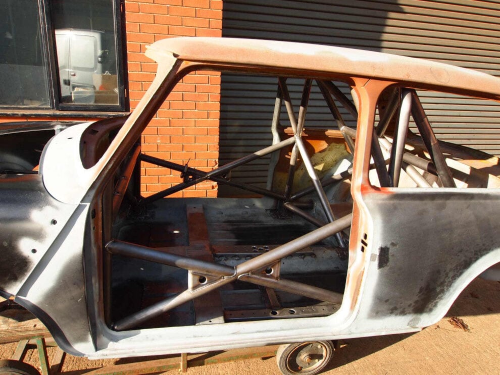 Bare classic Mini shell with a Custom Cages multipoint T45 roll cage fitted, showing the door bars and diagonal