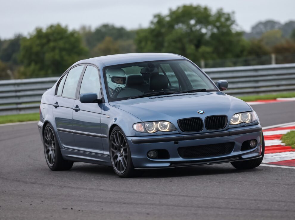 Steel Blue BMW 3 Series E46 on a British race circuit at an apex with red and white kerbing