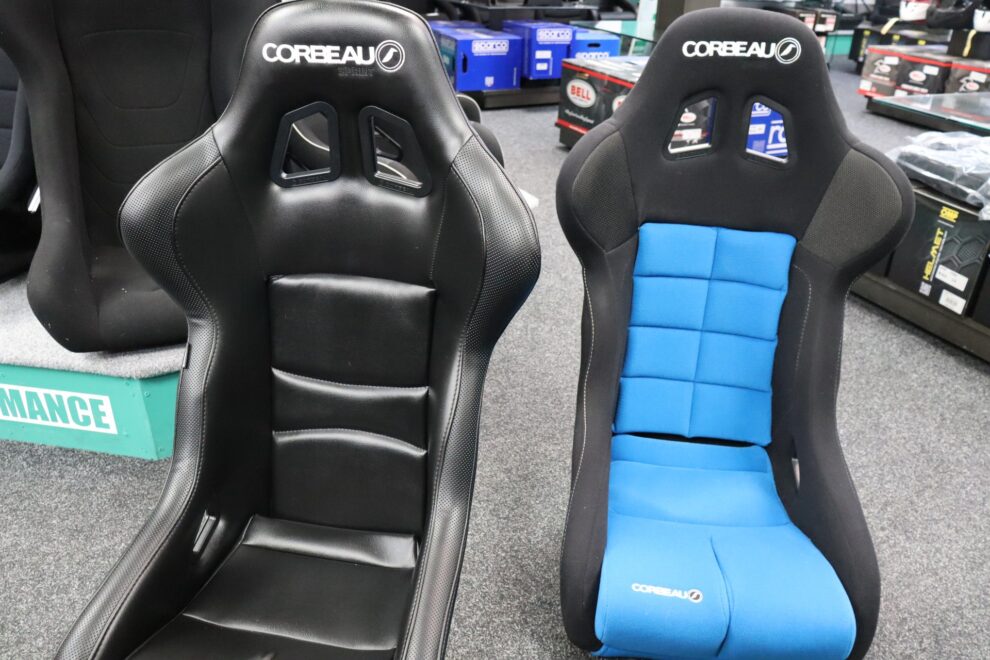 Black vinyl Corbeau bucket seat next to a fabric Corbeau bucket with a blue centre in the showroom