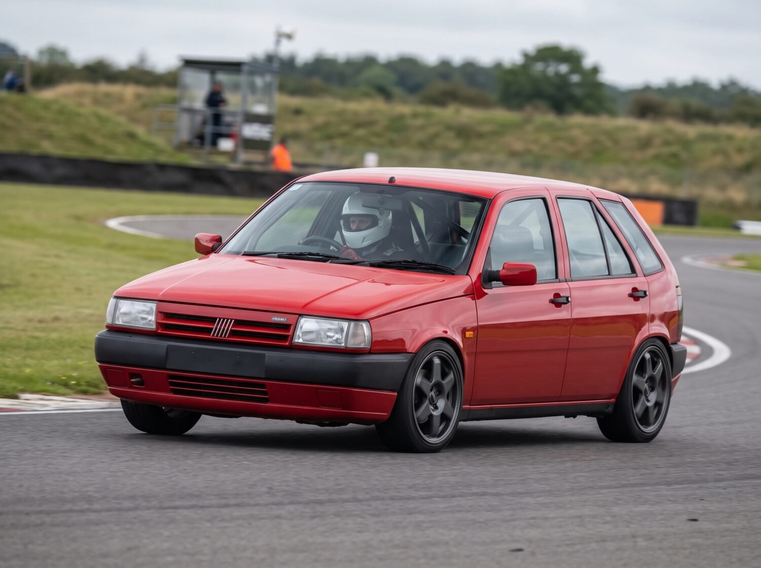 Red Fiat Tipo Mk1 accelerating out of a corner at a British club circuit