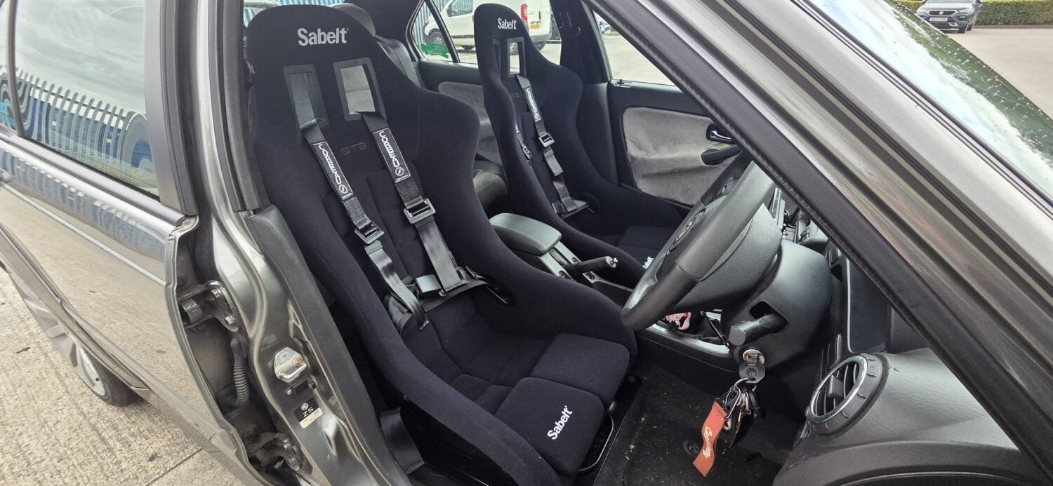 Pair of Sabelt GT3 bucket seats with black Corbeau three point harnesses fitted in a grey MG ZS, seen through the driver door