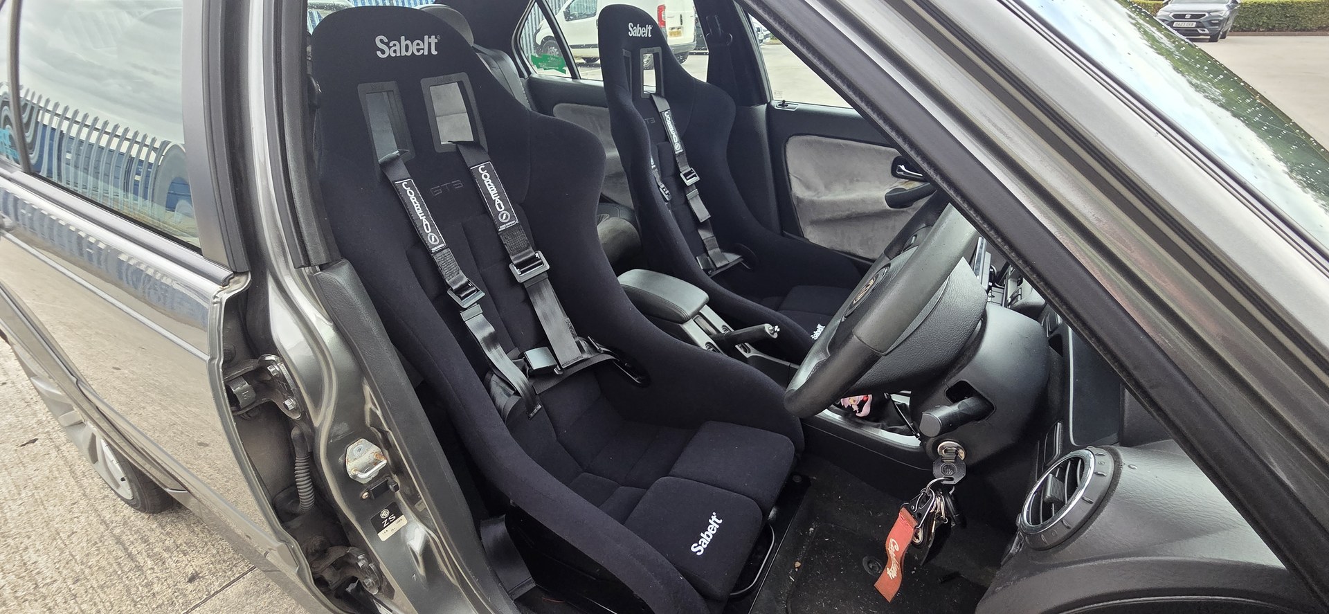 Pair of Sabelt GT3 bucket seats with black Corbeau three point harnesses fitted in a grey MG ZS, seen through the driver door