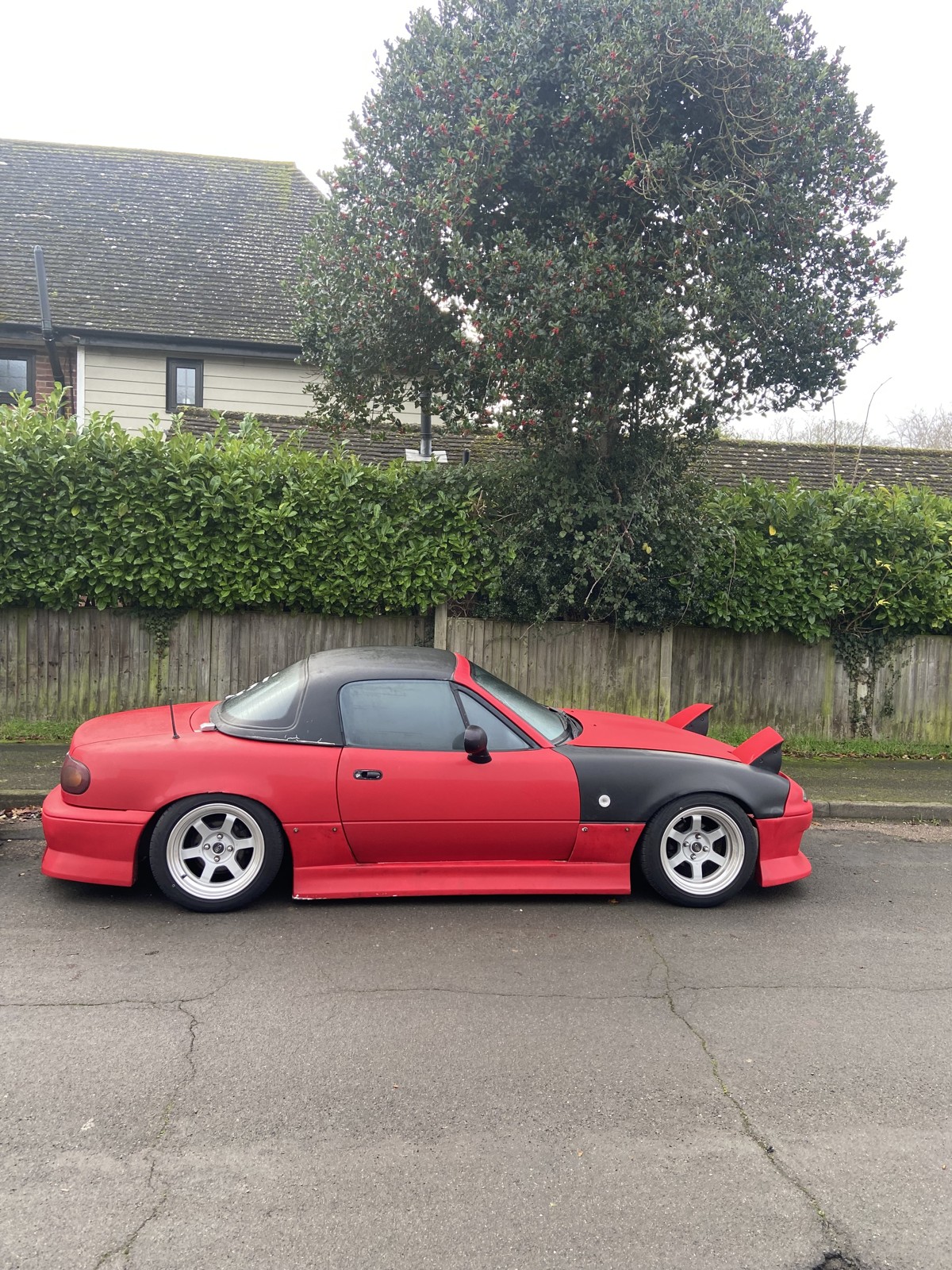 Red Mk1 MX-5 drift car with a mismatched black wing before the rebuild