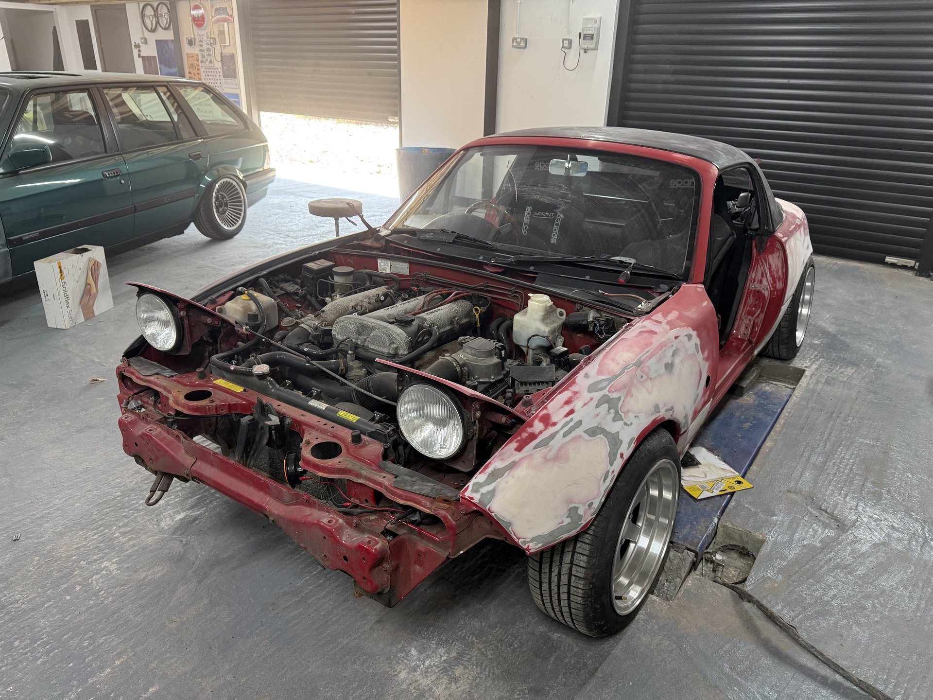 Mk1 MX-5 stripped to bare metal and filler in a workshop during bodywork