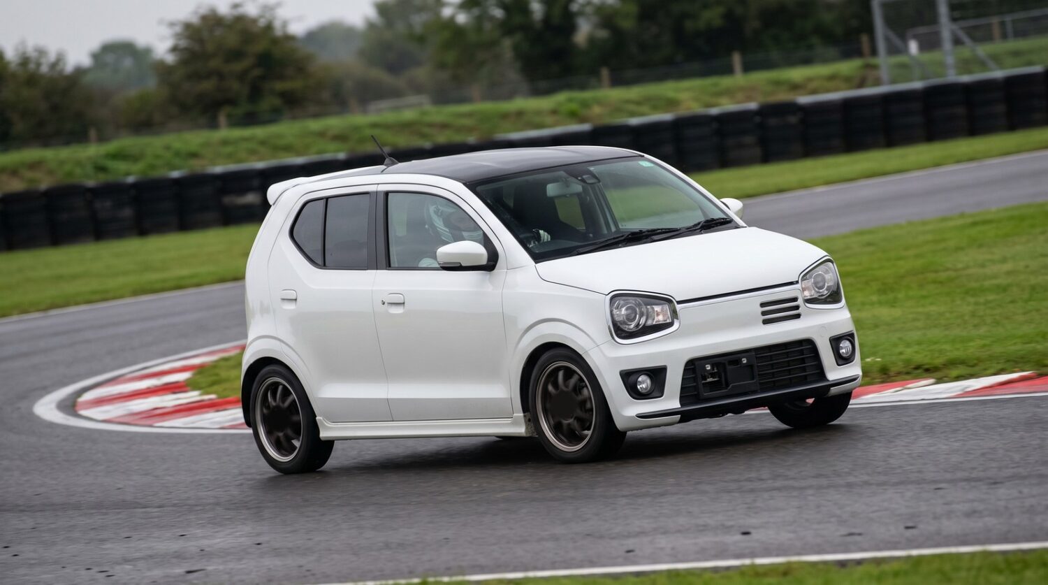 White Suzuki Alto Works HA36S kei hot hatch cornering at an apex on a British race circuit