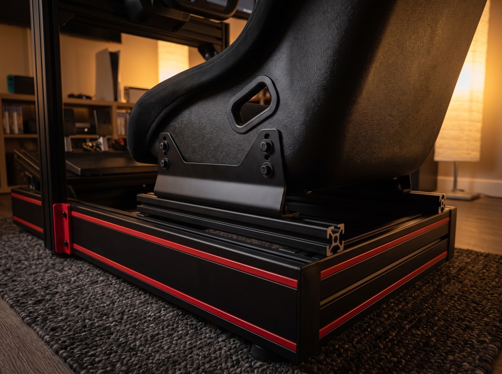Plain black bucket seat on steel side mount brackets bolted to the seat rails of a Trak Racer style rig with red striped skirt panels