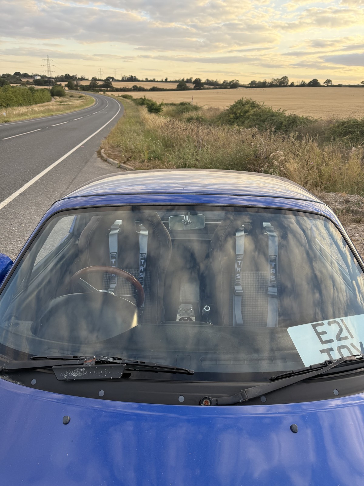 Silver TRS four point harnesses seen through the windscreen of a blue Mk1 MX-5