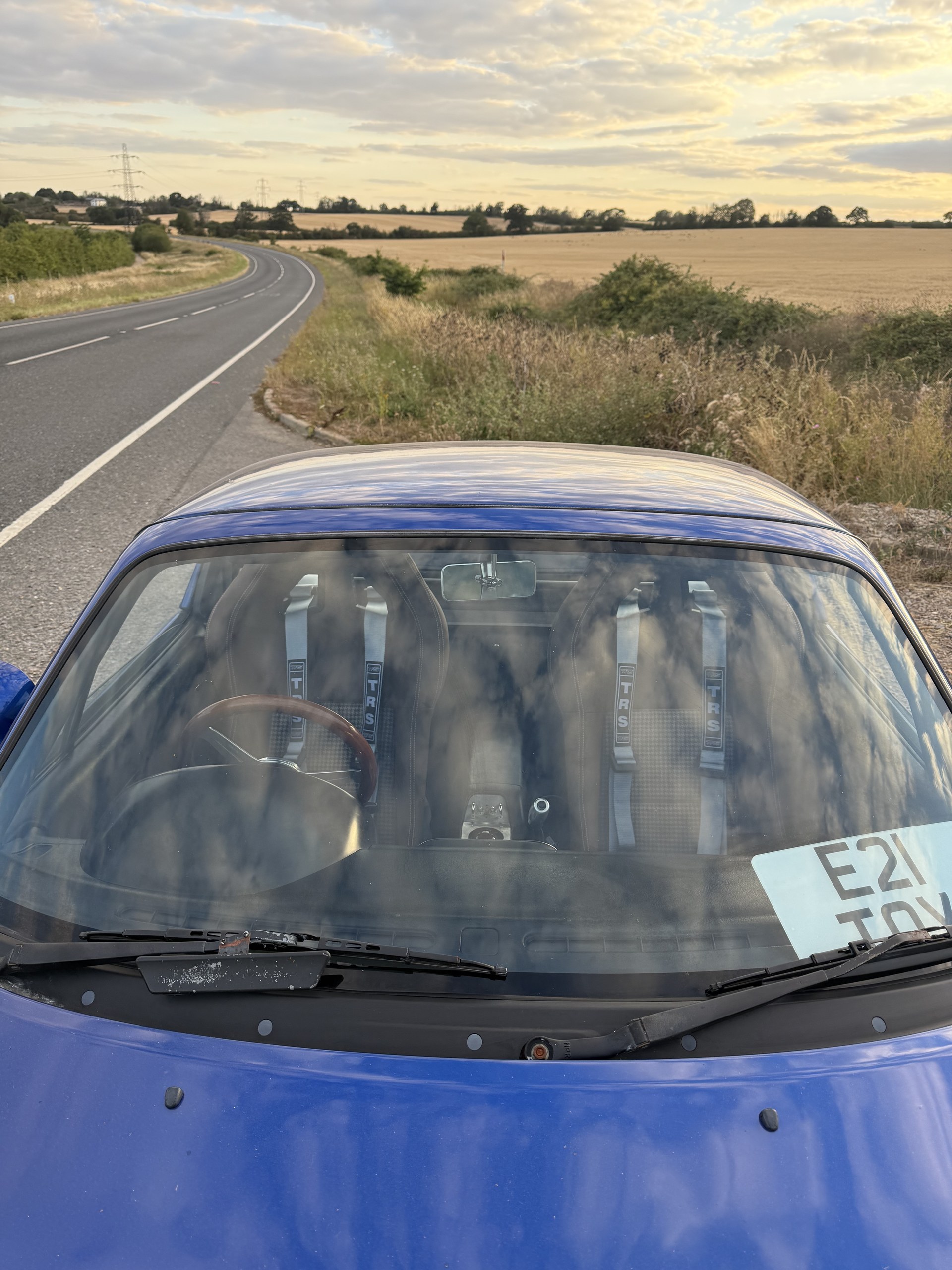 Silver TRS harnesses seen through the windscreen of a blue Mazda MX-5
