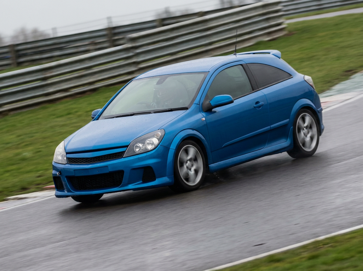 Blue Vauxhall Astra Mk5 three door sport hatchback cornering on a damp British race circuit