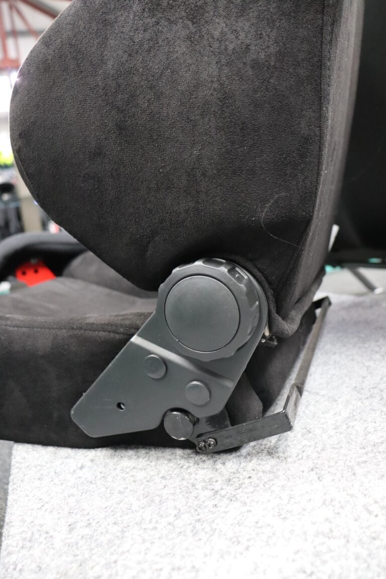 Close up of the round knurled hand wheel on the side of an Auto Style Type C reclining sports seat in black suede