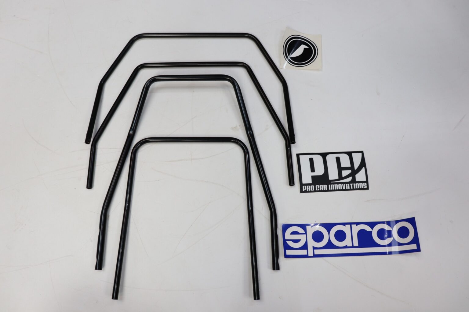 Three seat runner release handles of different widths nested inside one another beside PCI, Sparco and Corbeau stickers