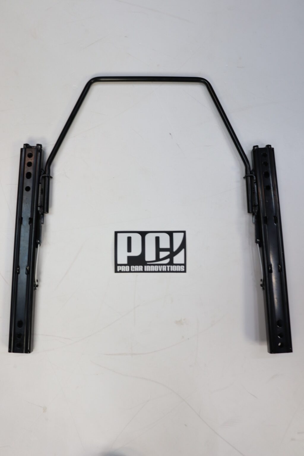 Complete PCI Racing universal seat slider kit laid out as it sits under a seat, beside the PCI sticker