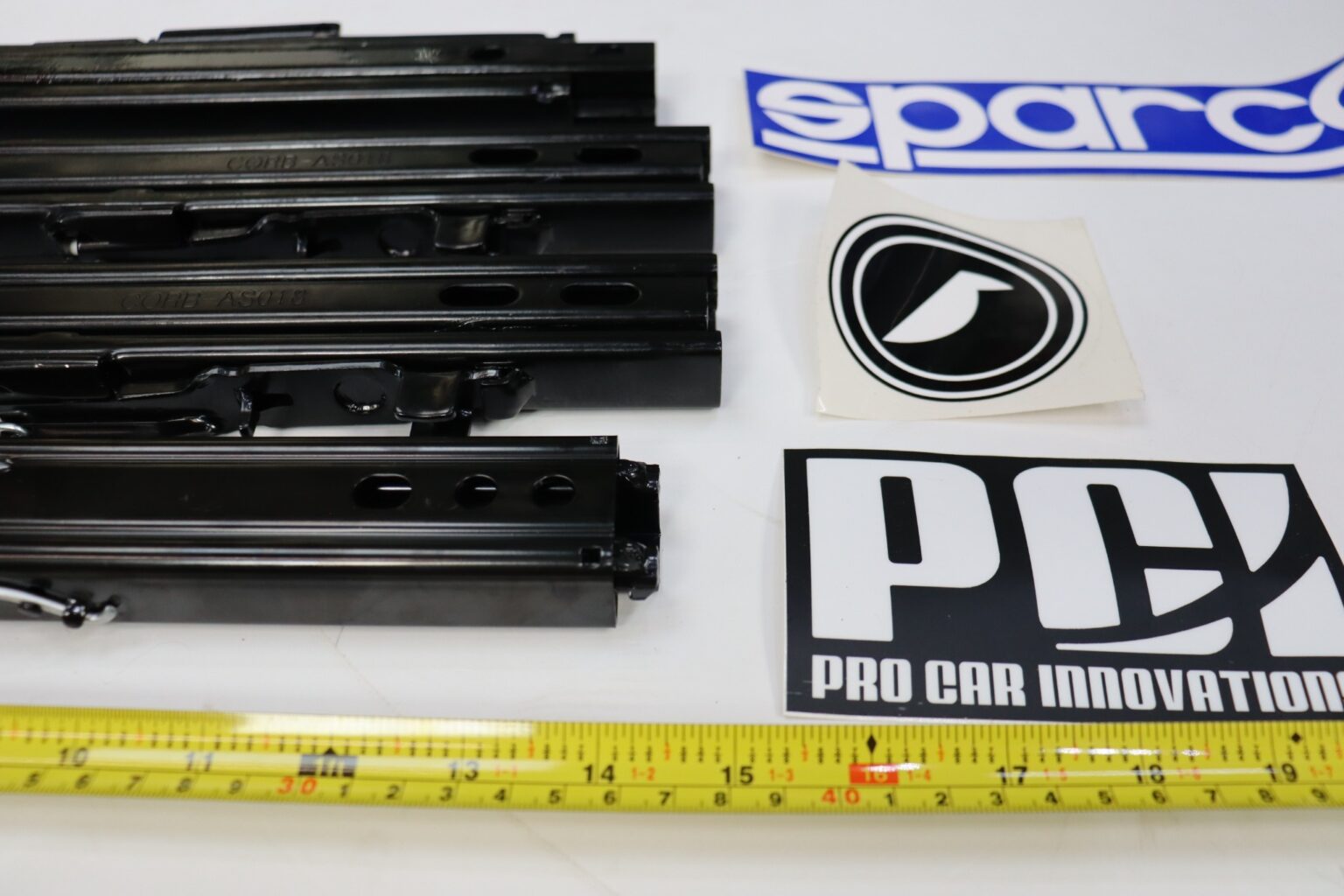 Seat sliding runner rails lined up on a workshop bench with a tape measure running alongside them