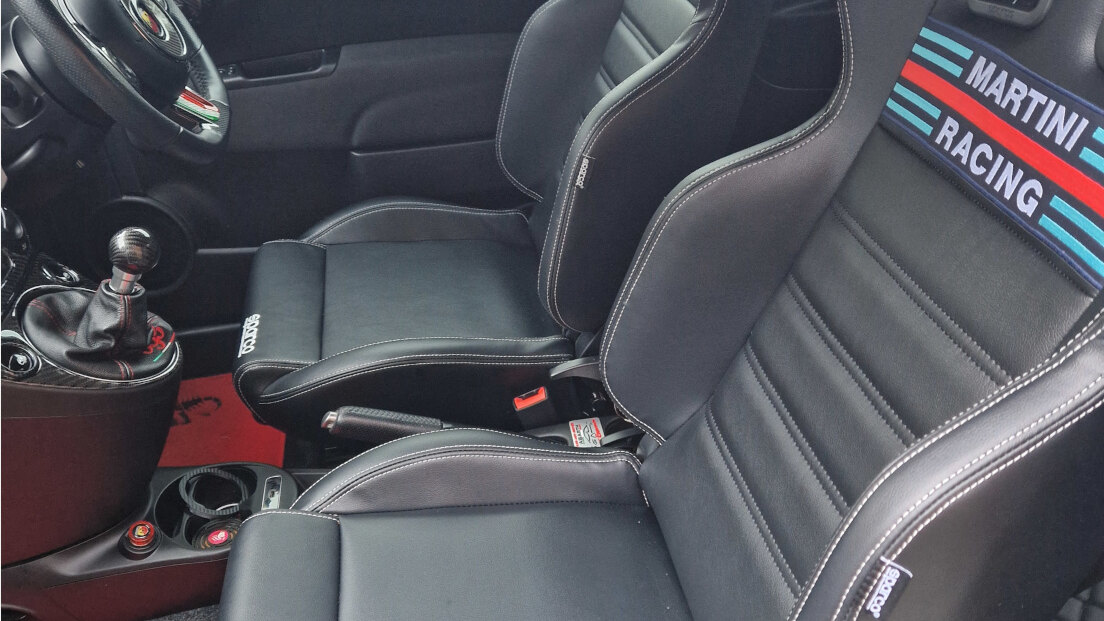 Two black Sparco R100 Martini Racing reclining seats fitted in the customer's Fiat Abarth 595, seen through the open door