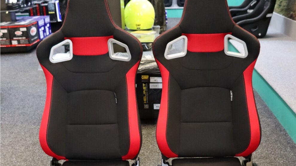 A pair of black and red Auto Style RS6-II reclining sports seats with silver harness slot surrounds in the SportSeats4u showroom