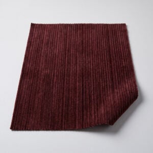 Swatch of burgundy fine wale corduroy upholstery fabric showing the narrow parallel ribs and soft nap