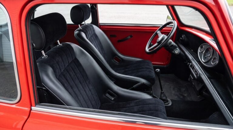Pair of black Cobra Classic GT bucket seats with ribbed cord centre panels and separate cylindrical headrests, fitted in a red classic Mini, seen through the wound down driver window over the top of the shut door