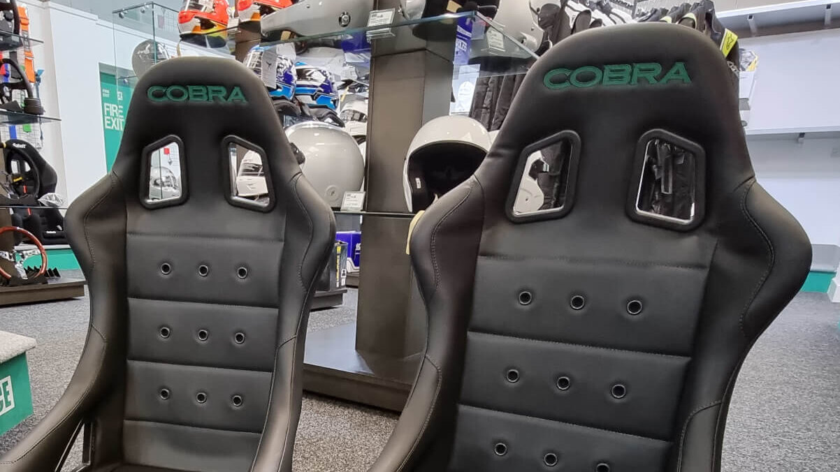 A pair of black Cobra Monaco 40th Edition bucket seats with green stitched Cobra logos in the GSM Performance showroom