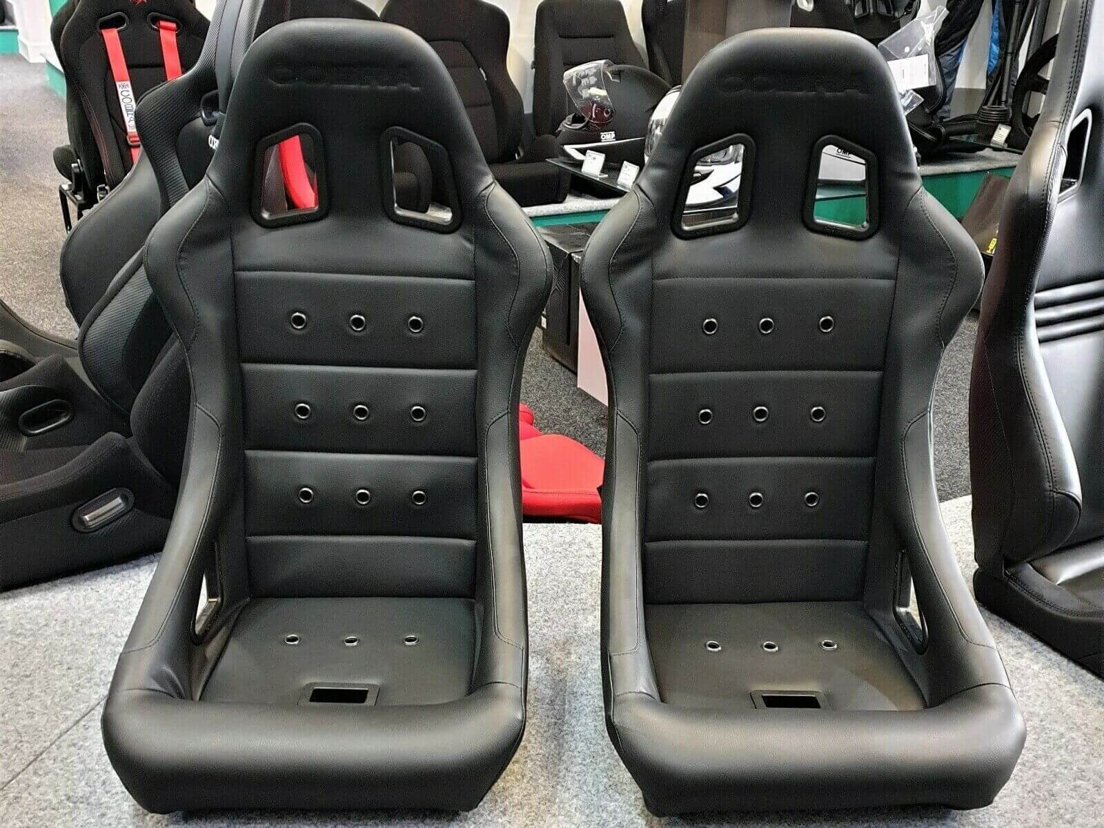 A pair of black Cobra Monaco Pro 40th Edition bucket seats with black stitching on the GSM Performance showroom plinth