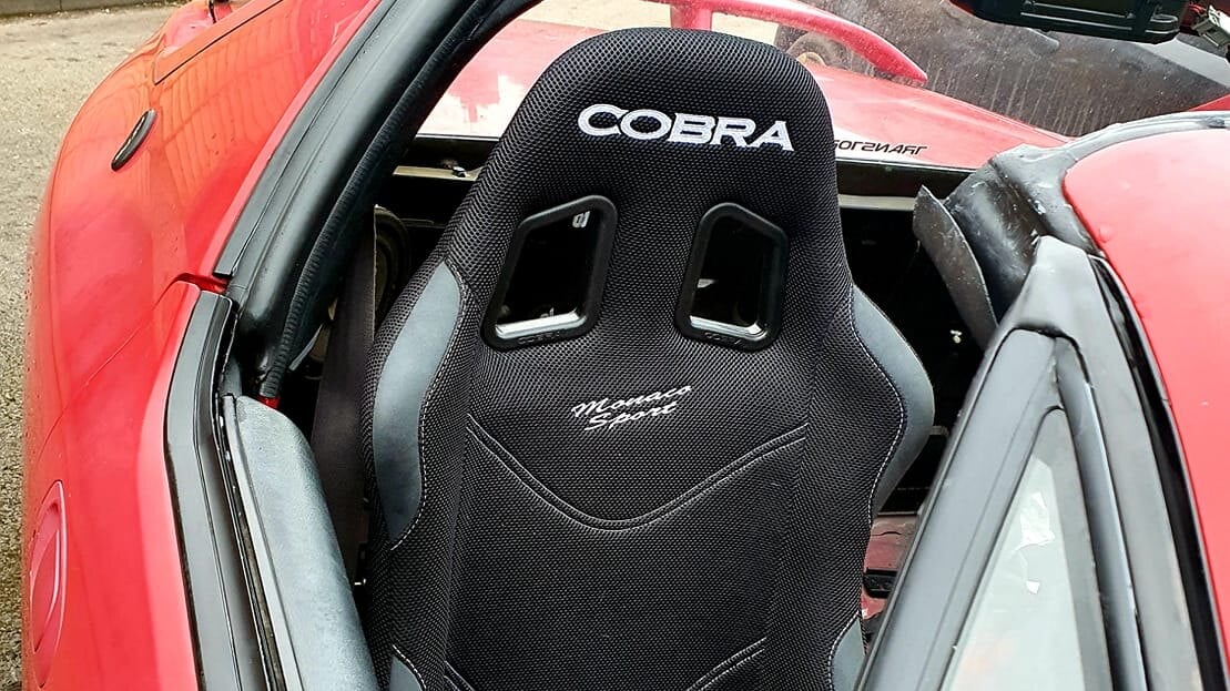 A black Cobra Monaco Sport bucket seat fitted in a customer's red Honda Del Sol, seen from above with the roof panel off