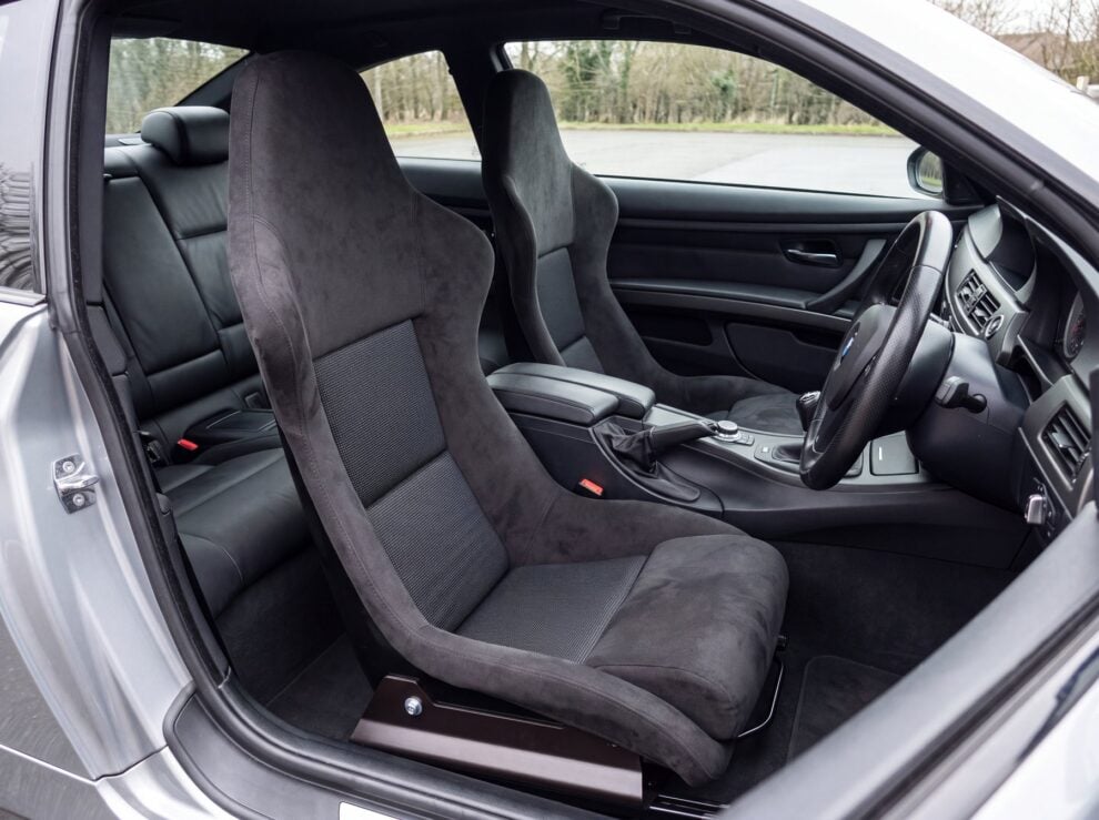 A pair of fixed back bucket seats on frames in a right hand drive BMW E92 M3 coupe, seen from the open passenger door
