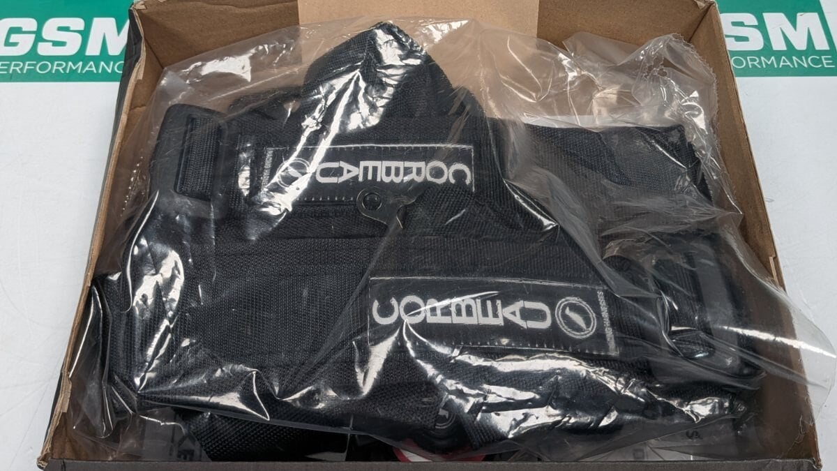 A black Corbeau harness in its bag inside an open Luke Racing Systems box