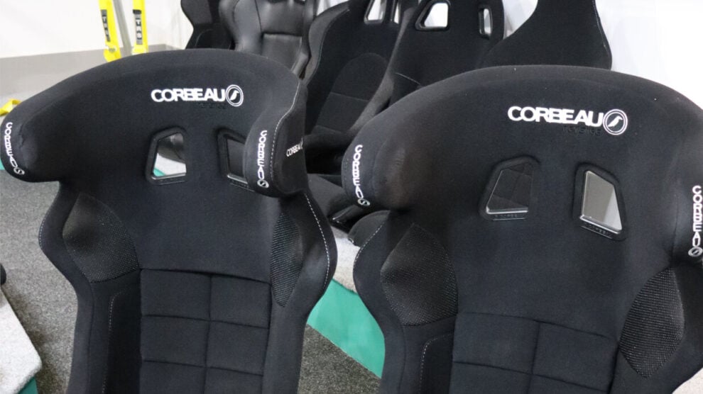 Two black Corbeau Revenge FIA bucket seats on the showroom floor, with more Corbeau seats on the display plinth behind