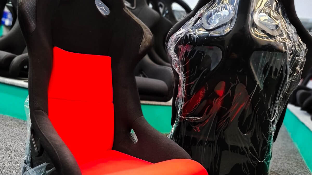 An Endurance Motorsport bucket seat with a red centre beside a wrapped black seat in the GSM Performance showroom