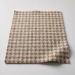 Swatch of oatmeal and brown Harris Tweed houndstooth upholstery cloth showing the woven wool texture