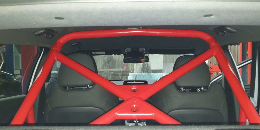 A red JP Cages half cage with X bracing seen from the boot of a Hyundai i30N