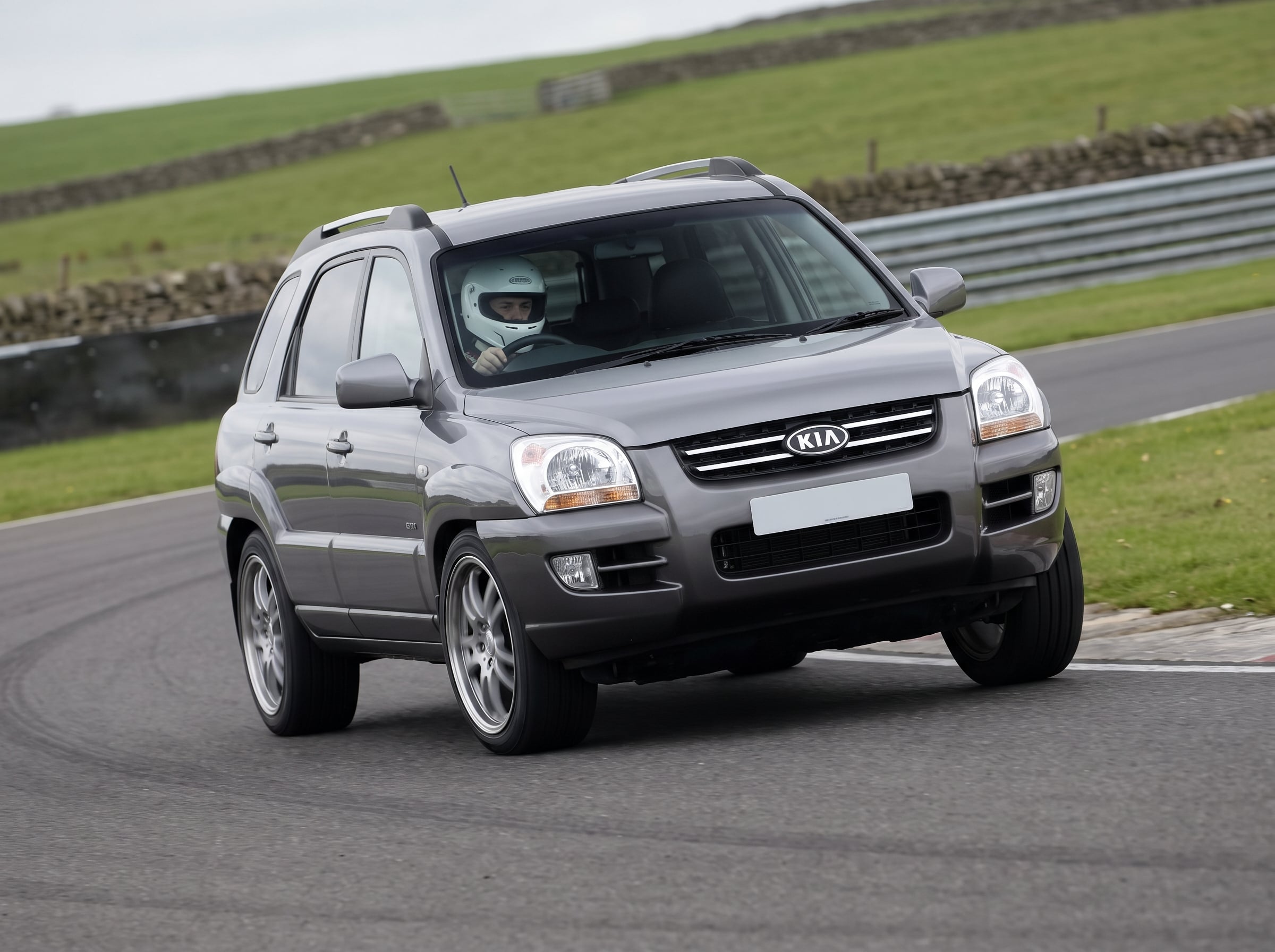 Kia Sportage 4x4 cornering on a British race circuit with helmeted driver visible